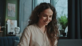 Close-up portrait of relaxed calm smiling young woman with long natural curly hair sitting at desktop in front of laptop and chatting with friends. Pleasant-looking girl enjoying online conversation - Powered by Shutterstock - Get 15% off with code: PIKWIZARD15