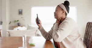 Ill unaltered african american woman using smartphone having video call with doctor, in slow motion. Lifestyle, healthcare, telemedicine, communication and domestic life.