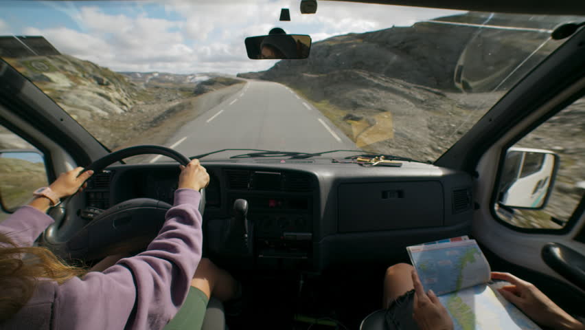 Two friends explore beautiful national park in Norway on camper van. Look at map to plan road trip, drive on small mountain road. Camper van or RV adventure concept Royalty-Free Stock Footage #1103978855