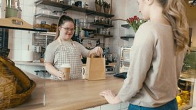 Caucasian woman with down syndrome passing take away food to a female client. Shot with RED helium camera in 8K.  