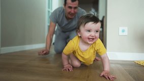 Happy family.Baby crawls on floor with his father.Girl smiles and crawls on floor of house.Dad plays with his daughter at home.Home kindergarten.Father day in kindergarten.Happy baby crawling on floor - Powered by Shutterstock - Get 15% off with code: PIKWIZARD15