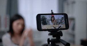 Handheld shot, Close-up phone view, Beautiful asian woman blogger is showing how to make up and use cosmetics. In front of the smartphone to record vlog video. Influencer and cosmetics concepts.