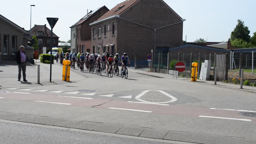 Wilsele, Vlaams-Brabant, Belgium - May 18, 2023: free access to women's local annual cycling race Ladies  Elite. Group racers taking a corner followed by a caravan of promotion car and ambulance