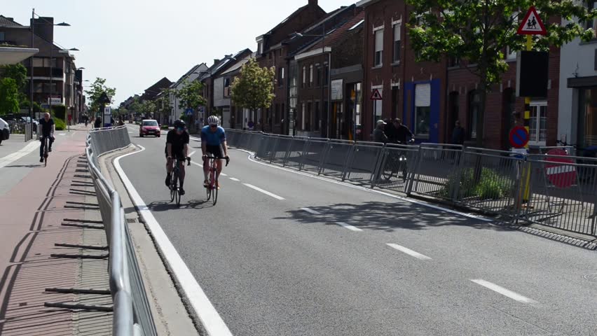 Wilsele, Vlaams-Brabant, Belgium - May 18, 2023: free entry to the local annual Ladies Elite cycling race for women. Cars and 2 hobby cyclists ride on race parcours when racers already passed