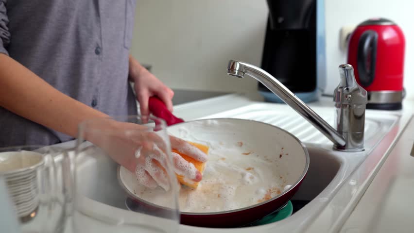 Women's hands wash greasy, burnt frying pan, with ceramic coating, washcloth and dishwashing detergent, in home kitchen. concept routine, manual housework, washing dishes Royalty-Free Stock Footage #1103985953