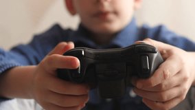an emotional child plays video games holding a joystick in his hands, a schoolboy gamer laughingly plays on a game console. a teenager has an addiction to games