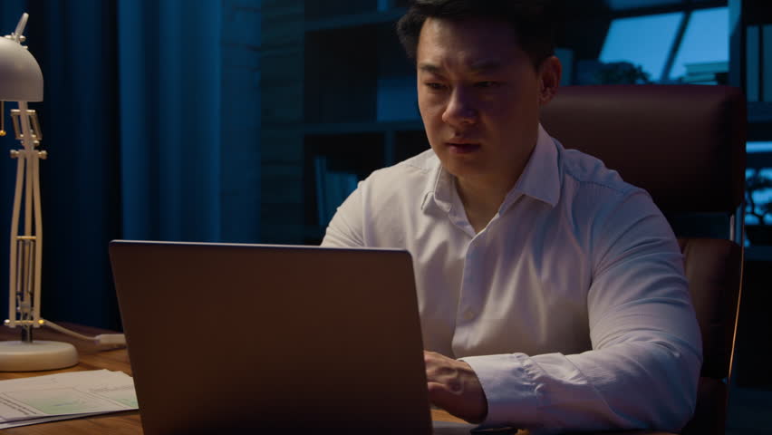 Asian stressed tired Korean man middle-aged exhausted overworked businessman laptop working problem paperwork business trouble bad result documents failure difficulties stress at night evening office Royalty-Free Stock Footage #1103993957