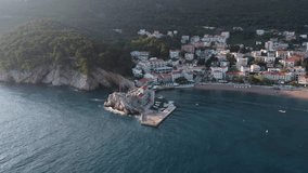 4k video. Montenegro. Old fortress and the city of Petrovac from the sea side at sunset. Shot by drone from a height of 200 m. 500 meters from the coast.