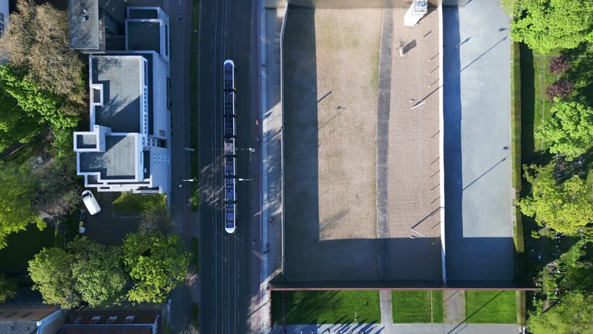 Long shadows of people in line. Stunning aerial top view flight Berlin Wall Memorial Border crossing zone, city district, Germany spring 2023. vertical bird's eye view drone
4k uhd cinematic footage.