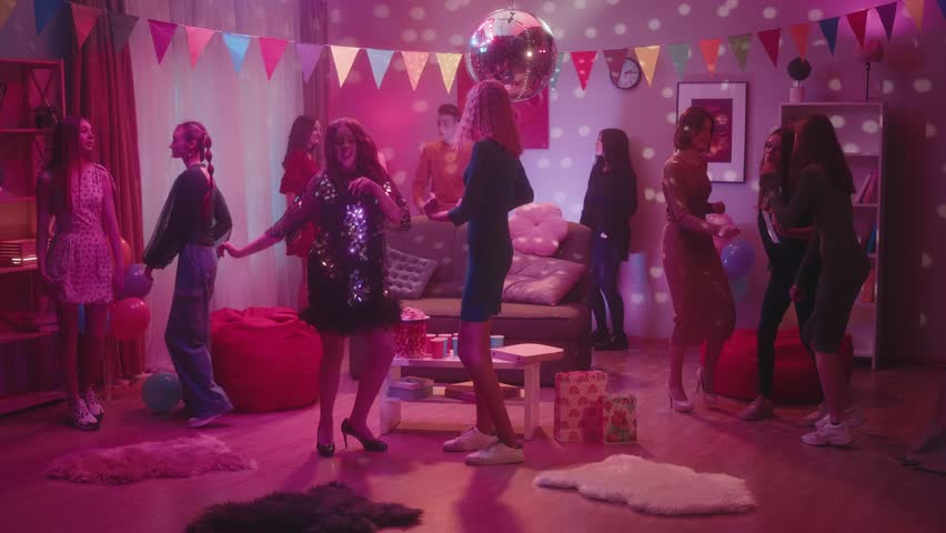 A company of teenagers dance incendiary at a house party, except for one informal girl. The girl keeps aloof feeling awkward and uncomfortable. The interior of the room is decorated for the party. Royalty-Free Stock Footage #1104004217