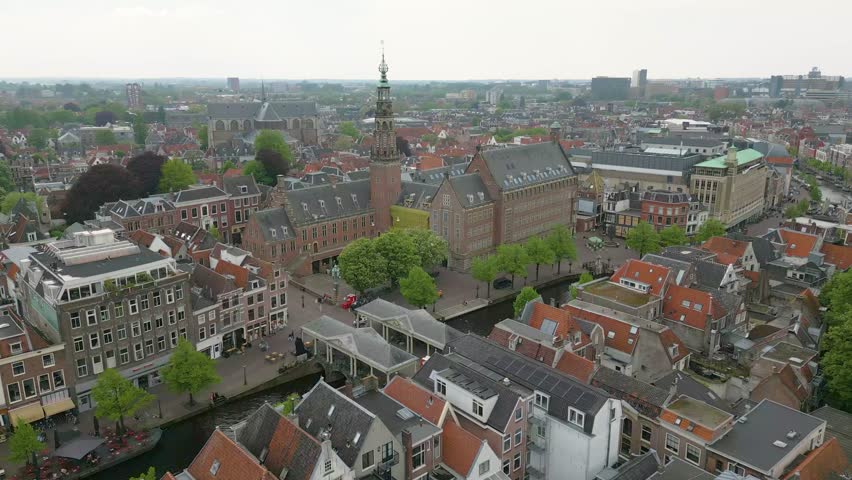 This aerial drone video shows the beautiful old city of Leiden, Zuid-Holland, the Netherlands. In this shot you can see some canals with typical dutch canal houses. 