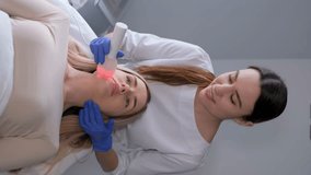 Vertical video of a woman undergoing a facial phonophoresis procedure with gel in a beauty salon