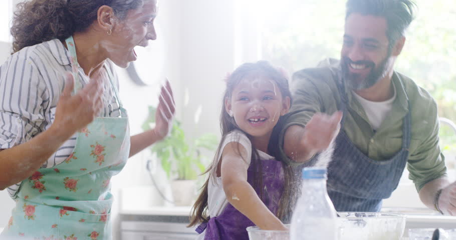 Flour, funny and family play after baking in kitchen or food fight, mother and dad laughing with happiness in home. Mom, father and girl cooking mess, crazy and quality time together in house