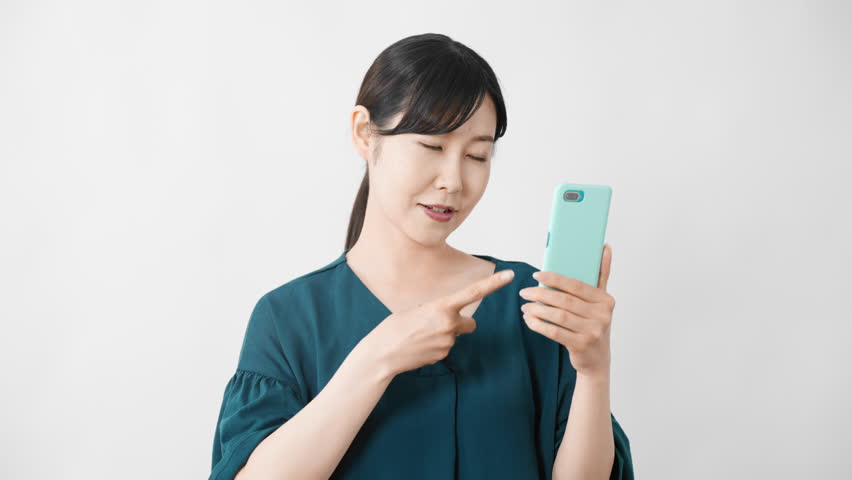 Young woman pointing while holding a smartphone