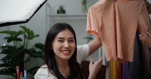 Footage close up shot of Young Beautiful Asian women live streaming to sale new fashion clothes at home studio, They enjoy to talking in front of digital camera, influencer on social media concept