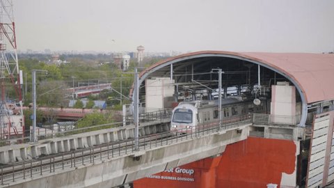 A modern metro train is leaving or departing a subway station with the urban city landscape is visible in the background Redaksjonell arkivvideo