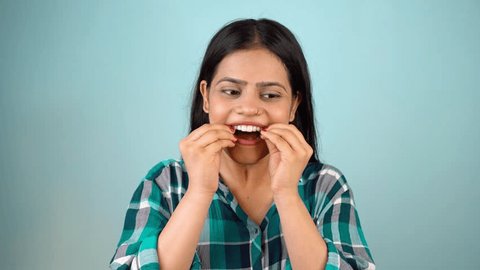 Young Asian Indian woman holding removable invisible aligner, also known as invisalign or  clear aligner 库存视频