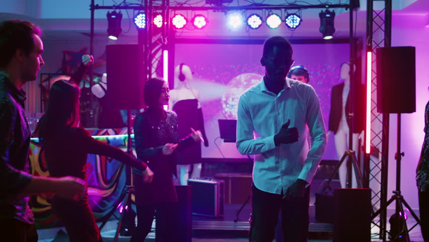 Happy man dancing with people at club, having fun on funky cool music at discotheque. Young person partying and jumping around on dance floor, social gathering at bar. Handheld shot. | Shutterstock HD Video #1104023439