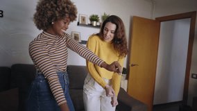 Girlfriends dancing together fun in living room apartment. Young multiracial lesbian couple shooting video for music clip. Bloggers making content for a social media channel. Friends partying at home 