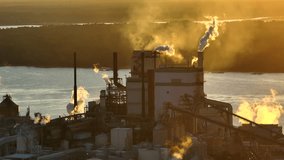 Large factory structure with smoke from production process rising up polluting atmosphere at manufacturing yard. Industrial site at sunset - Powered by Shutterstock - Get 15% off with code: PIKWIZARD15