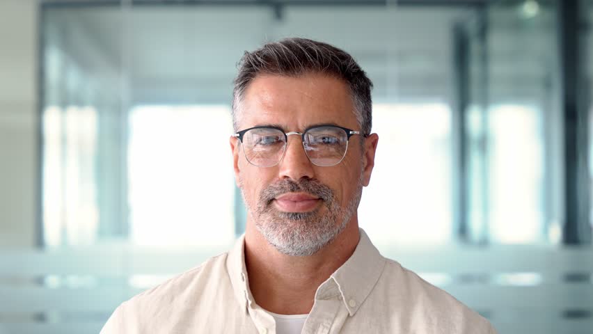 Headshot close up portrait of indian or latin confident mature good looking middle age leader, ceo male businessman on blur office background. Handsome hispanic senior business man looking at camera. | Shutterstock HD Video #1104036173