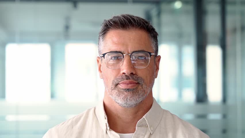 Headshot close up portrait of indian or latin confident mature good looking middle age leader, ceo male businessman on blur office background. Handsome hispanic senior business man looking at camera. | Shutterstock HD Video #1104036173