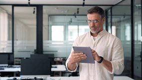 Happy Latin Hispanic bearded stylish mature adult professional business man, smiling Indian senior businessman CEO holding digital tablet using fintech tab application standing inside company office. - Powered by Shutterstock - Get 15% off with code: PIKWIZARD15