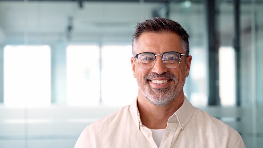 Headshot close up portrait of indian or latin confident mature good looking middle age leader, ceo male businessman on blur office background. Handsome hispanic senior business man smiling at camera. | Shutterstock HD Video #1104036177