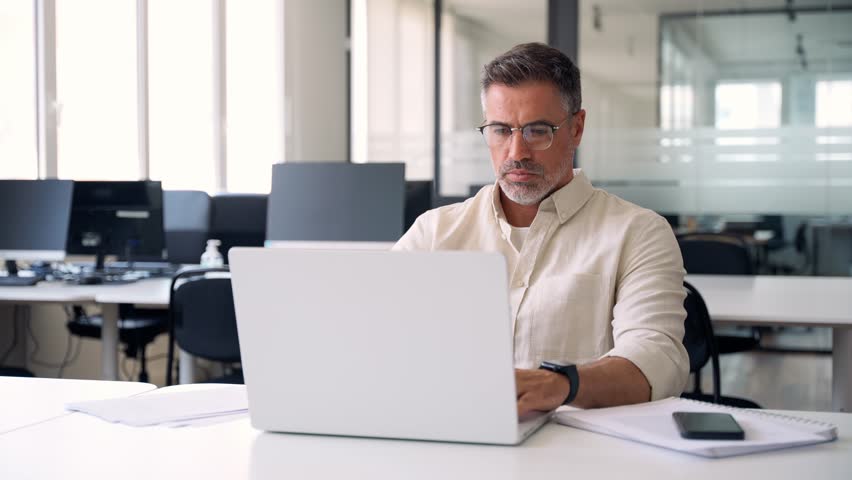Mature Indian or Latin business man ceo trader using computer, typing, working in modern office, doing online data market analysis, thinking planning tech strategy looking at laptop with copy space. Royalty-Free Stock Footage #1104036185