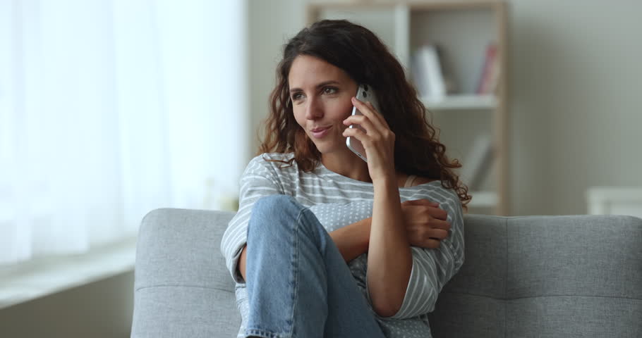 Carefree Hispanic woman relaxing on couch, spend free time at home, enjoy personal conversation on cell phone, communicates remotely with boyfriend, share news, use modern tech and mobile connection Royalty-Free Stock Footage #1104040023