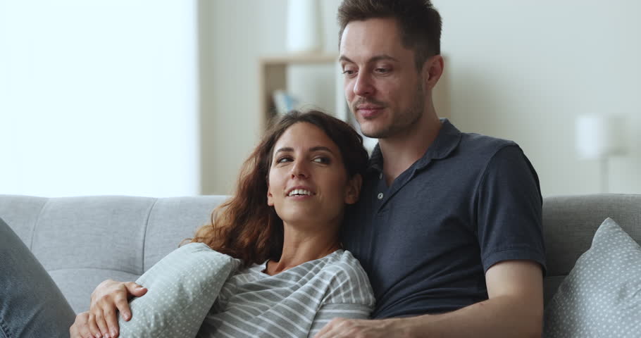 Close up Hispanic young couple in love relax on sofa in living room enjoy talk, share dreams, hugging, daydreaming together feel carefree, enjoy romantic date, planning bright future at new own house Royalty-Free Stock Footage #1104040055