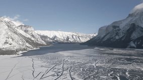 Aerial video flies over a frozen lake in Banff National Park in winter