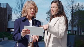 Two female executives gathered outdoors to review business statistics and data on the digital tablet - Powered by Shutterstock - Get 15% off with code: PIKWIZARD15