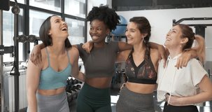 Mulitethnic group of woman embracing and smiling in a gym