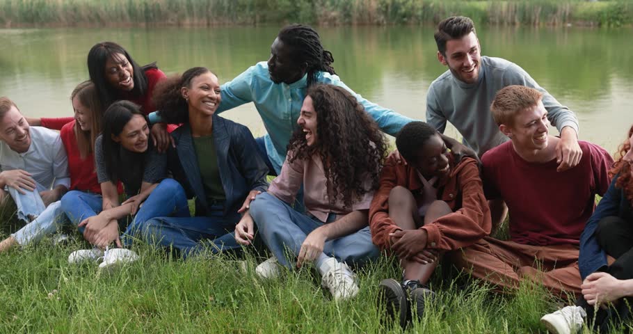 Multiethnic friends having fun together sitting on grass next to the lake outdoor Royalty-Free Stock Footage #1104071769