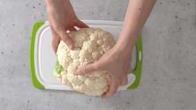 Cauliflower on cutting board in woman's hands, the cooking process, flat lay