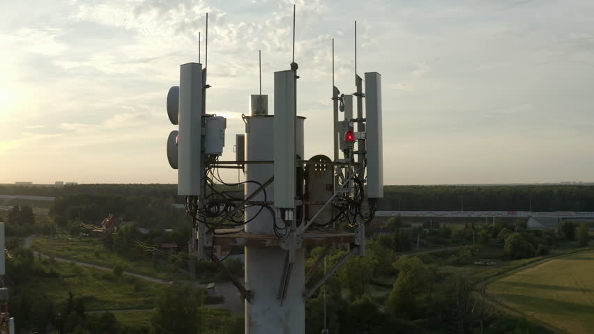 Drone flying around cell tower antennas, base station transmitting 5g, 4g signals in countryside. Royalty-Free Stock Footage #1104072803