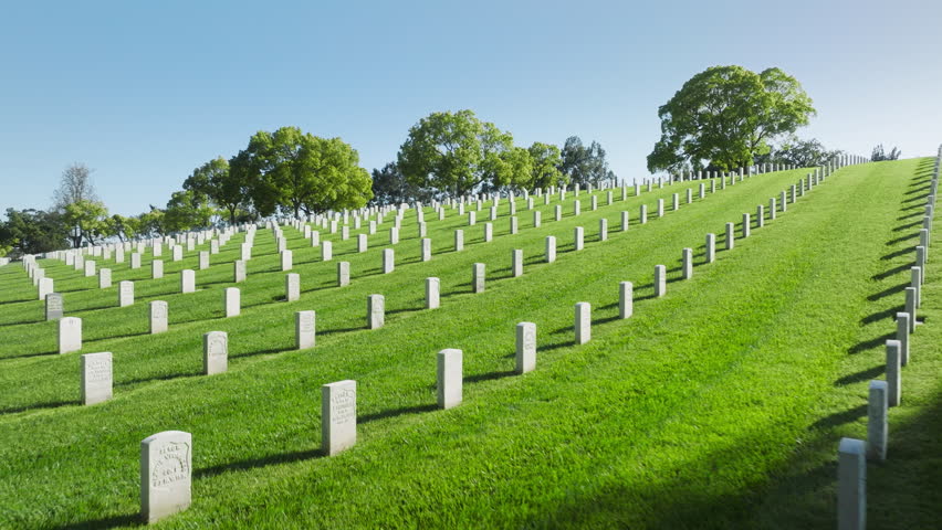 Peaceful funeral concept. Aerial Los Angeles National Cemetery California USA. Drone flying above scenic green field with straight rows white grave plates on summer day. Armed forces national cemetery Royalty-Free Stock Footage #1104074177
