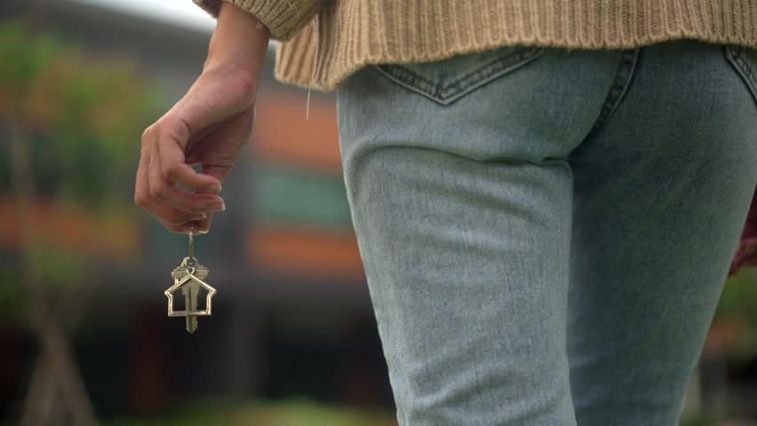 Close up shot of hand holding key woman buying or rent new home walking to new house. First time to renter or purchase apartment, home. Moving day relocate concept. Royalty-Free Stock Footage #1104079125