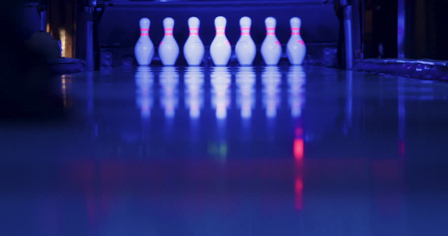 The man gracefully releases the bowling ball, which glides down the lane with incredible accuracy, striking all the pins in a single throw and achieving a strike in bowling. Royalty-Free Stock Footage #1104080939
