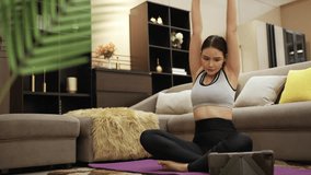 Young attractive Asian woman in sportswear learning workout exercise by watching exercise tutorials online class on laptop computer in living room with black cat on couch at home. Home fitness concept