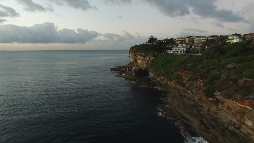 Fly along cliffs by the ocean, early morning light.