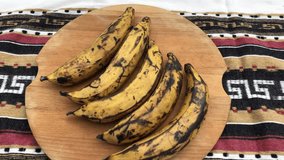 Top view and slow motion spin video of 5 plantains on a wooden chopping board