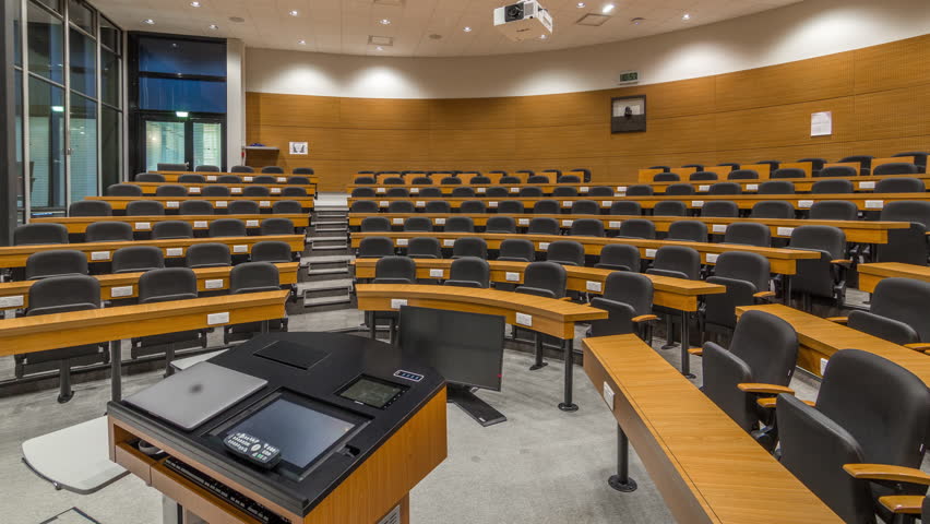 A wood panelled university lecture theatre or conference hall in business school timelapse. Laptop and remote control on the table