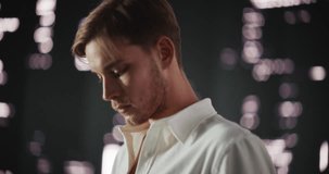Fashion Footage in a Cyberspace Futuristic World: Young Male Poses with Confidence, Looking From Side to Side, Standing in Front of an Abstract Dark Studio Setting with Artistic Digital Animation