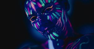 Expressive Portrait: Beautiful Young Woman with Neon Body Paint Engages the Camera, Transmitting a Sense of Mystery and Captivation Through Her Intense Gaze and Striking Appearance