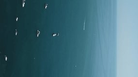 Aerial yacht on calm sea. Luxury cruise trip. View from above of white boat on deep blue water. Aerial view of rich yacht sailing sea. Summer journey on luxury ship. Vertical video