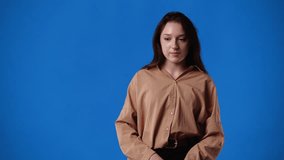4k video of one girl who showing something in her right hand over blue background.