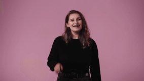 4k video of one woman who pointing the finger at someone and laughing over pink background.