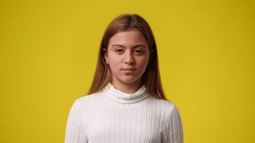 4k video of one young girl who posing and smiling over yellow background.